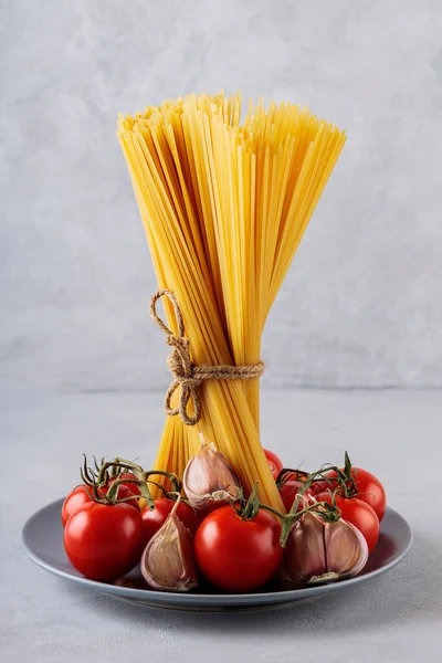 스파게티 파스타에 토마토와 마늘을 곁들인 드라이 이탈리아 파스타와 야채가 클로즈업 — 스톡 사진