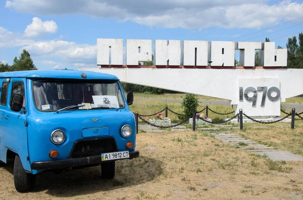 Blue van stopped in front of the Prypiat welcome sign, Chernobyl exclusion zone, Ukraine. High quality photo