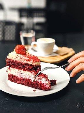 Bir fincan kahveyle bir parça kek ve beyaz tabakta siyah çikolata.