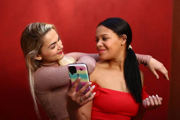 Фото Двух Довольно Счастливых Женщин Использующих Свои Смартфоны Розовом Фоне — стоковое фото