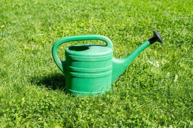 Yeşil çimlerde büyük yeşil bir plastik bahçe sulama kutusu.