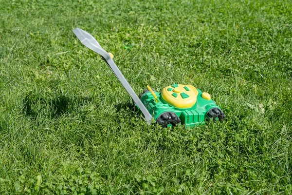 未伐採の草の上の子供のおもちゃ芝刈り機 — ストック写真