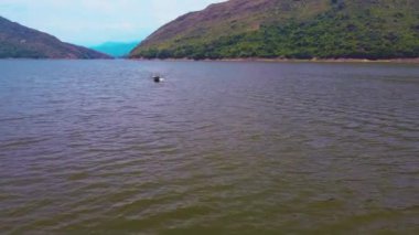 Kolombiya 'da Prado Tolima barajını tekneyle geçen adam. Suyun üzerinde bir tekne ya da motorbot sürme konsepti. 