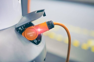 Elektrik kablosu prize takılı olan şarj istasyonundaki EV Car veya Electric Car, Modern Çevre dostu enerji sürücü aracı