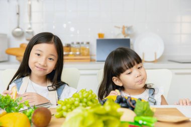 İki Asyalı kız kardeşin portresi. Birlikte oynuyorlar ve birlikte yemek yiyorlar..