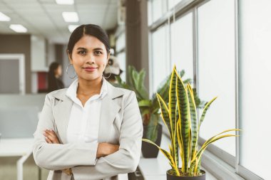 Asyalı iş kadınlarının portresi mutlu gülümseyen ofis pencerelerinden geçerken kolları üzerinde durdukları için kendilerine güveniyorlar