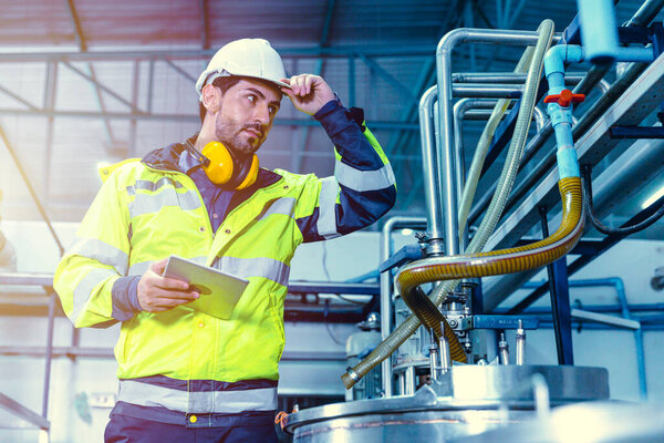 Factory worker Hispanic engineer working in factory checking maintenance pipe boiler system in factory.