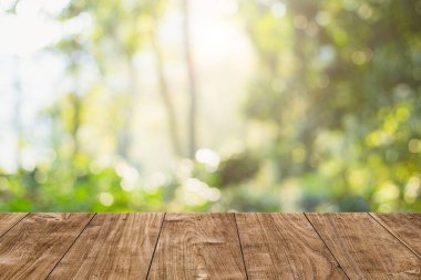 Kurgu ürünleri için ahşap masa üstü bulanık sabah aydınlık ormanı ile yeşil doğa reklam arkaplanı