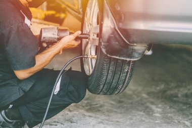 Otomobil tekerleği ve garajda çalışan tamirci.