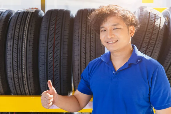 Car tire on shelf with salesman sale agent happy to service in tyre shop. Good quality vehicle tire, people recommended and promotion.