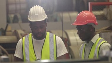 Afrikalı siyahi mühendis ustabaşı, yeni personel çalışanına iş görüşmesi sürecini açıklıyor.
