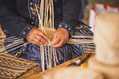 Sepet ya da tepsi için bambu şeritleri ören Asyalı kadın el işi..
