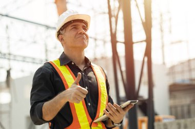 Professional Caucasian Engineer male builder working at construction site work outdoor with safety thumbs up.