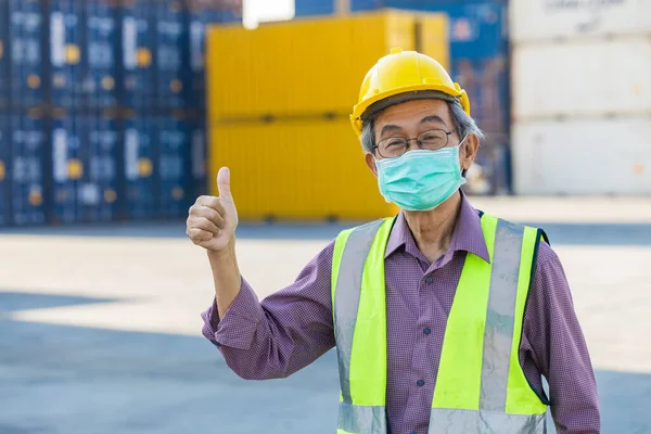 healthy elder senior worker with face mask thumb up. Asian chinese old man engineer staff foreman good healthcare.