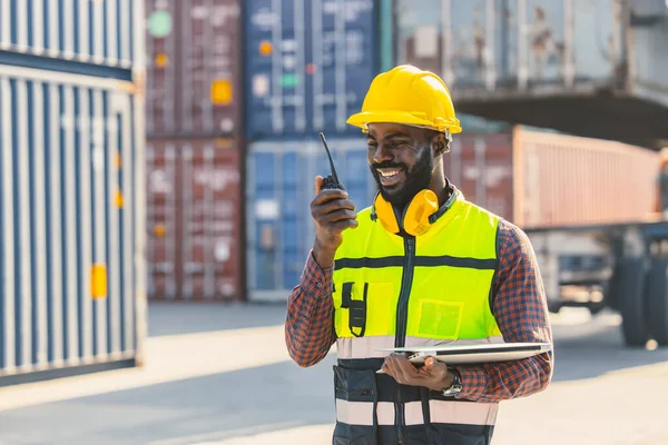 black worker African working engineer foreman radio control in port cargo shipping customs container yard