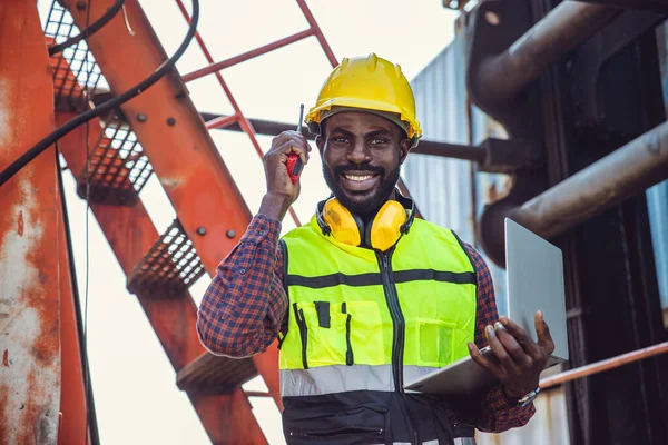 black worker African working engineer foreman radio control in port cargo shipping customs container yard