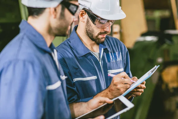 Team Industry Engineers worker in metal Factory using Digital Tablet Computer talking discussion help together.