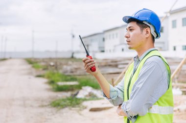 İşçi ustabaşı mühendis inşaat sahasının güvenlik kontrolünde radyo komutu kullanarak çalışıyor..