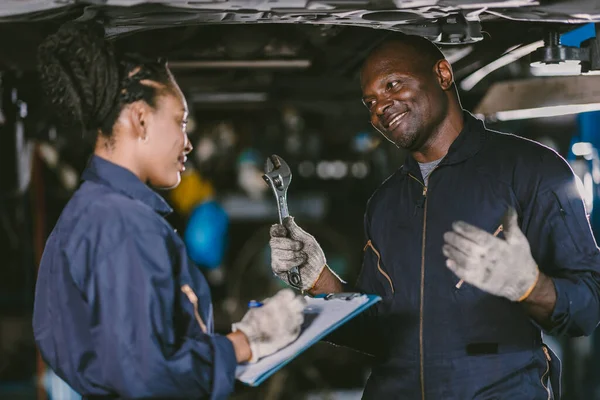 Auto garage worker Black African working together to fix under car service working togerher walking smile