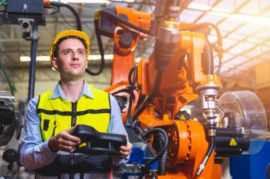 Kafkas mühendisi erkek işçi metal fabrikasında robot kaynak makinesi denetleyicisi ve monitörü ile çalışıyor..