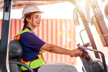 Depoda çalışan kadın forklift operatörü. Forklift 'te oturan ve gülümseyen genç Hintli kadın sürücünün portresi büyük bir depoda çalışıyordu.