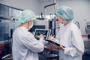 Food and Drink factory worker working together with hygiene monitor control mix ingredients machine with laptop computer