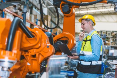 Kafkas mühendisi erkek işçi metal fabrikasında robot kaynak makinesi denetleyicisi ve monitörü ile çalışıyor..