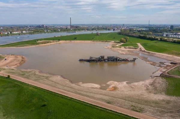 Gravel and sand extraction at the river Rhine, in the city of Duisburg, using a gravel extractor.