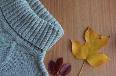 Sıcak örgü süveter ve sarı yapraklar masanın üzerinde..