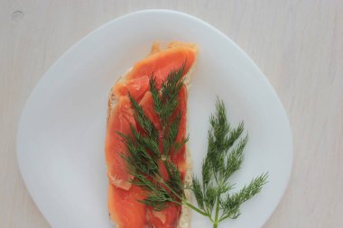 Tereyağlı sandviç, kırmızı balık ve dereotu tabakta..