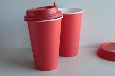 Kırmızı kağıt bardaklar hafif bir yüzeyde duruyor..