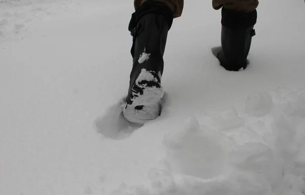 穿着黑靴子在雪地里行走的人的脚 — 图库照片