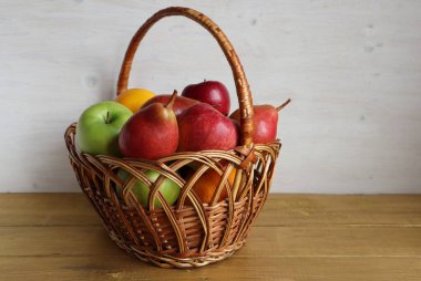 Bir sepet meyve, elma ve armut masada duruyor..