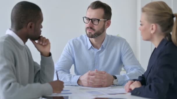 Серьезный бизнесмен беседует с деловыми людьми в офисе — стоковое видео