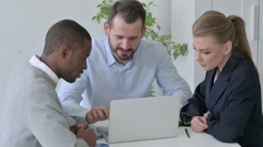 Ofiste dizüstü bilgisayar kullanırken Karışık Irk İşadamları Başarıyı Kutluyor 