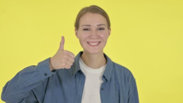 在黄色背景上显示拇指向上标志的年轻女子 — 图库视频影像