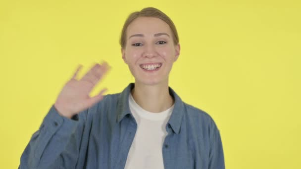 Jonge vrouw zwaaien, verwelkomen op gele achtergrond — Stockvideo