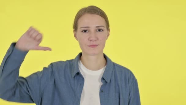Duimen omlaag gebaar van jonge vrouw op gele achtergrond — Stockvideo