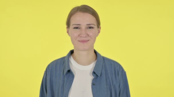 Νεαρή γυναίκα χαμογελώντας στην κάμερα σε κίτρινο φόντο — Αρχείο Βίντεο