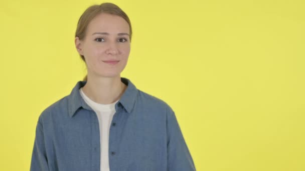 Joven mujer sosteniendo el producto en la mano sobre fondo amarillo — Vídeos de Stock