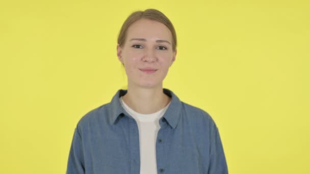 Mujer joven mostrando la forma del corazón por las manos sobre fondo amarillo — Vídeos de Stock