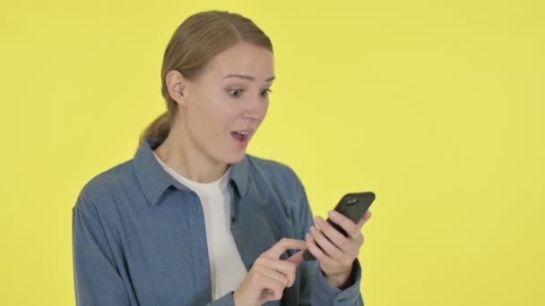 Jonge vrouw viert feest op Smartphone op gele achtergrond — Stockvideo