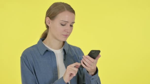 Mujer joven navegando Smartphone sobre fondo amarillo — Vídeo de stock