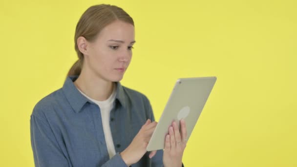 Jonge vrouw reageert op verlies op tablet op gele achtergrond — Stockvideo