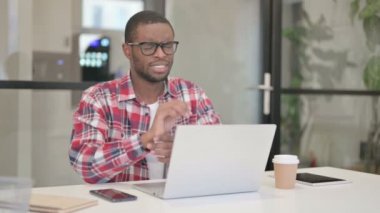 Dizüstü bilgisayar kullanırken bileği ağrıyan Afrikalı adam 