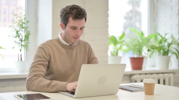 Людина, яка страждає від болю, користуючись ноутбуком в офісі — стокове відео