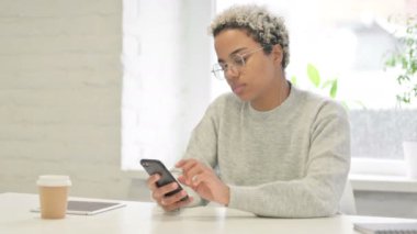 Ofiste akıllı telefon kullanan çekici Afrikalı kadın. 