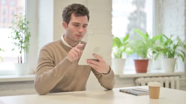 Людина, яка сидить в офісі на планшеті — стокове відео