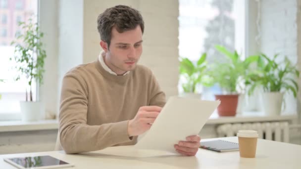 Людина святкує успіх, читаючи документи в офісі — стокове відео