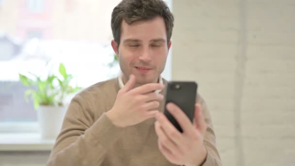 Hombre hablando de videollamada en el teléfono inteligente en la oficina — Vídeo de stock
